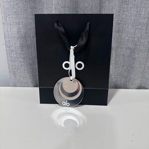 ALO black and white, empty paper bag with tissue paper and holiday gift charm.